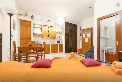 a bedroom with a large orange bed and a kitchen at San Giovanni In Laterano Daniela Apartment in Rome
