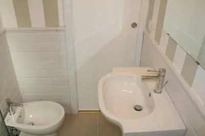 a white bathroom with a toilet and a sink at L'Incantevole Aventino in Rome