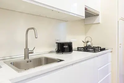 a white kitchen with a stove and a sink at Elegant Salandra Suite in Rome