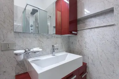 a bathroom with a white sink and a red cabinet at Navona New Deluxe Apartment in Rome