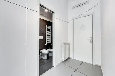 a white bathroom with a toilet and a mirror at The Upper Suites in Rome