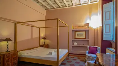 a bedroom with a canopy bed and a chair at EasyTopStay - Campo de' Fiori Pinky House in Rome