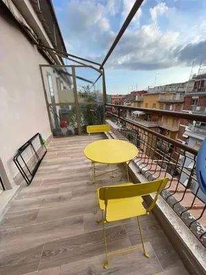 a yellow table and two chairs on a balcony at 2Effe apartment in Rome
