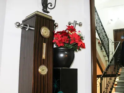 a clock next to a vase with red flowers next to a staircase at Casa Vacanze Scalone in Rome