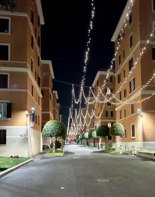 an empty street with christmas lights hanging from buildings at Viale dei Re di Roma in Rome