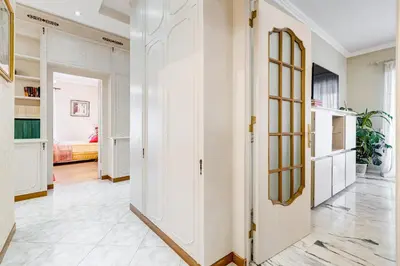 a hallway with white walls and a door with a mirror at Royal Vatican house JND in Rome