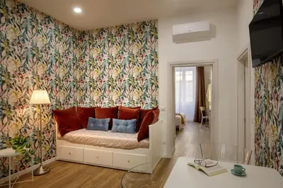 a living room with a couch with floral wallpaper at Remember Vatican Apartment in Rome