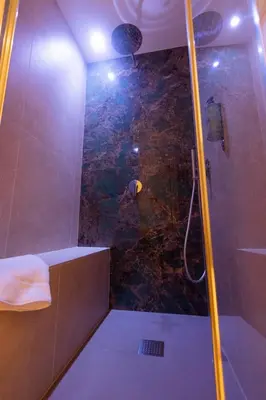 a bathroom with a shower with a stone wall at Trevi Monti House in Rome