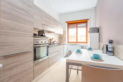 a kitchen with wooden cabinets and a table with chairs at St Peters Colorful 3BDR Apartment in Rome