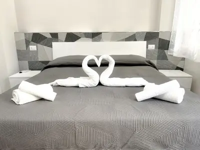 two white swans forming a heart on a bed at Niva holiday house in Rome