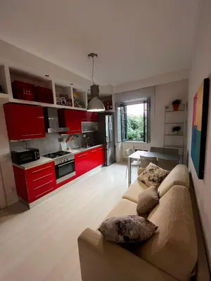a living room with a couch and a kitchen with red cabinets at Procida's House by ACS HOLIDAYS in Rome