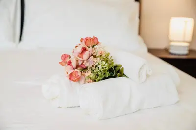 a white bed with towels and a bouquet of flowers at Domusky Attico - 8 piano in Rome