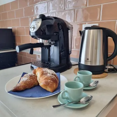 a table with a coffee maker and a plate of bread at Suite Station Tiburtina in Rome
