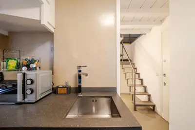 a kitchen with a stainless steel sink and a staircase at Maison Campo De Fiori in Rome