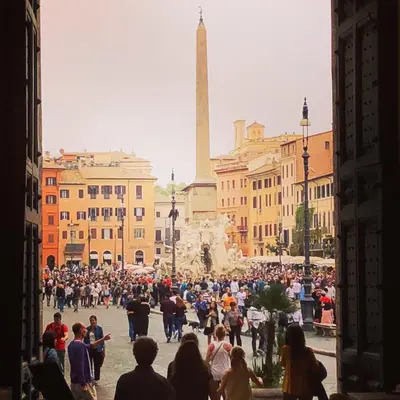 a crowd of people walking around a city with a monument at RHOMENJOY Open Space Colosseo in Rome