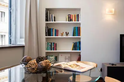 a glass table with a book shelf with books at Sant'Angelo Terrace Apartment in Rome