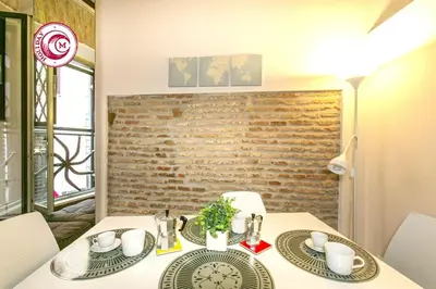a dining room with a table and chairs and a brick wall at C M Via Veneto Sweet Apartment in Rome