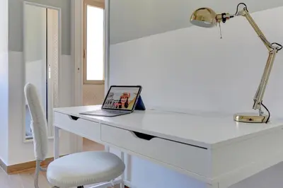 a laptop on a white desk with a lamp and a chair at Furio Camillo Studio - Metro A - Netflix in Rome