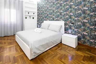 a bedroom with a white bed and a floral wallpaper at La Casa Di Alice in Rome