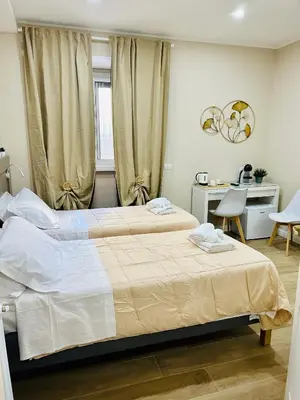 two beds in a hotel room with a desk and a desk at Segesta Rooms in Rome