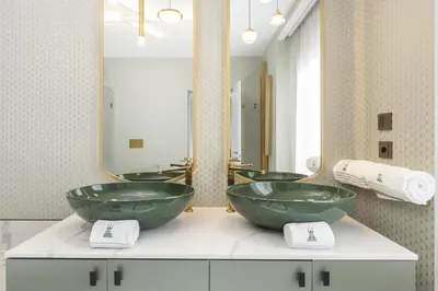 a bathroom with two green sinks and a large mirror at Tritone Luxury Suites Piazza del Popolo in Rome