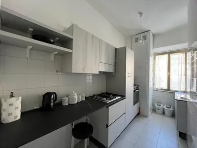 a kitchen with white cabinets and a black counter top at Veniero Apartment in Rome