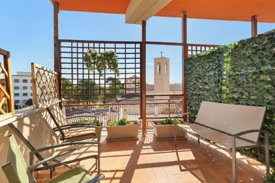 a balcony with chairs and a clock tower in the background at Adelante Rooms San Giovanni in Rome