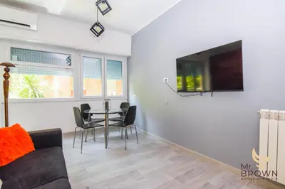 a living room with a table and a tv on a wall at Orange House in Rome