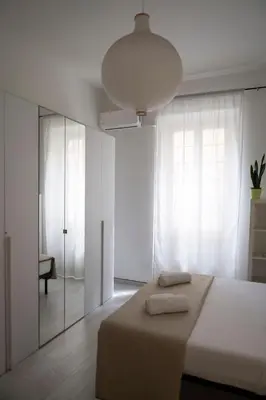 a white bedroom with a bed and a large window at Artist Vatican House in Rome