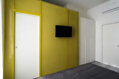a room with a yellow wall with a tv on it at B&B Girovagando in Rome