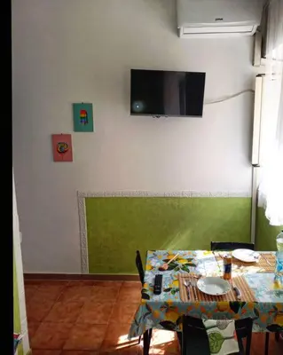 a dining room with a table and a television on a wall at Green House Roma in Rome