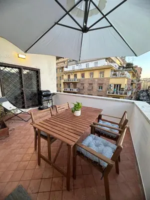 a wooden table and chairs with an umbrella on a balcony at L'Attichetto di via Padova in Rome