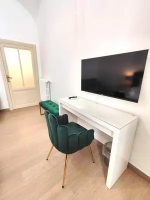 a white desk with a television and a green chair at The Gold Apartment in Rome