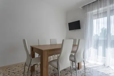 a dining room with a wooden table and white chairs at Rebecca Apartment in Rome