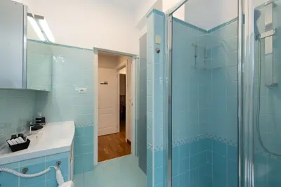 a blue bathroom with a shower and a sink at Querini Suite Roma in Rome