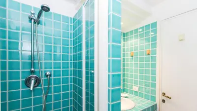 a blue tiled bathroom with a shower and a toilet at Scala Studio by Rental in Rome in Rome