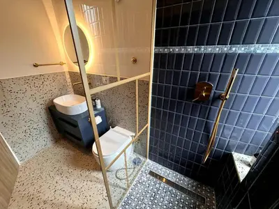 a bathroom with a toilet and a blue tiled wall at Kaizen The Barista 3BR Apartment With Coffee Station in Rome