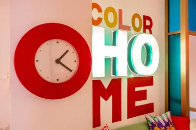 a red clock on a wall with a colo me sign at ColoRHome in Rome