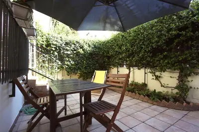 a table and chairs with an umbrella on a patio at Ponte Milvio Lovely Garden in Rome