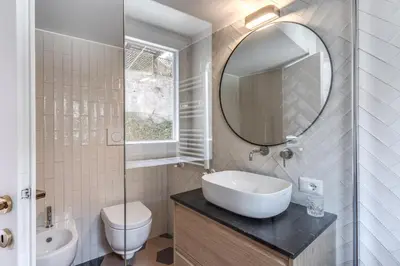 a white bathroom with a sink and a mirror at Cisterna 8 in Rome