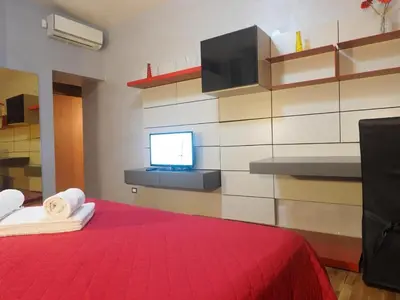a bedroom with a red bed with a tv on a wall at House Borgia in Rome