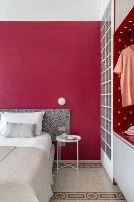 a bedroom with a red wall with a bed and a table at Ehi Bnb in Rome
