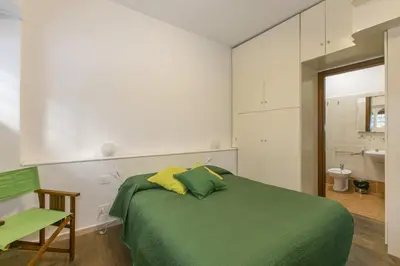 a bedroom with a green bed and a bathroom at Arbia Stay in Rome