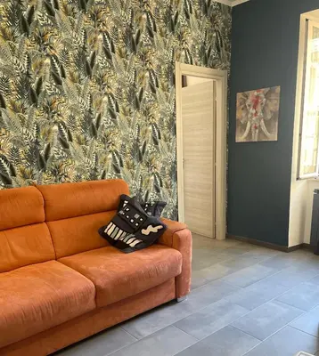 an orange couch in a living room with a wallpaper at Casa Gaia - Cozy Urban Oasis in Rome