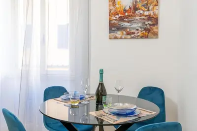a dining room with a glass table and blue chairs at Metro A 3 fermate da San Pietro - 2 Camere Luminoso - Domus Valeria in Rome