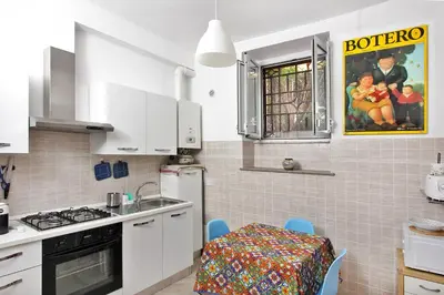 a kitchen with white cabinets and a table with a tablecloth at La maisonette romana in Rome