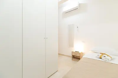 a white bedroom with a bed and a mirror at Casa Sole in Rome