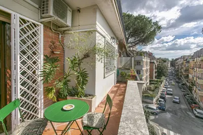 a balcony with a green table and a street at Rosso Levanto House in Rome