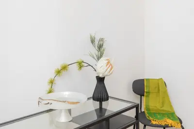 a glass table with a black vase with a flower on it at iFlat Bright Brand New 3-Bedroom Apt in Monti in Rome