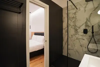 a bathroom with a walk in shower next to a bedroom at No Man's Land Guesthouse in Rome